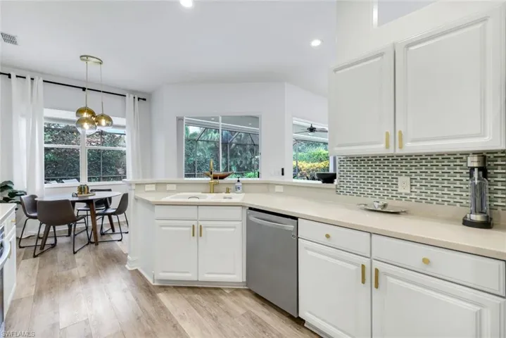 Kitchen with decorative light fixtures, dishwasher, decorative backsplash, and white cabinetry