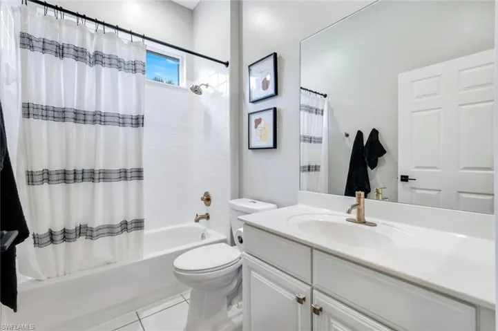 Bathroom with shower / bath combination, vanity, and tile patterned floors