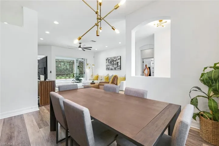 Dining area featuring light wood-type LVT flooring, recessed lighting, a chandelier, and arched walkways