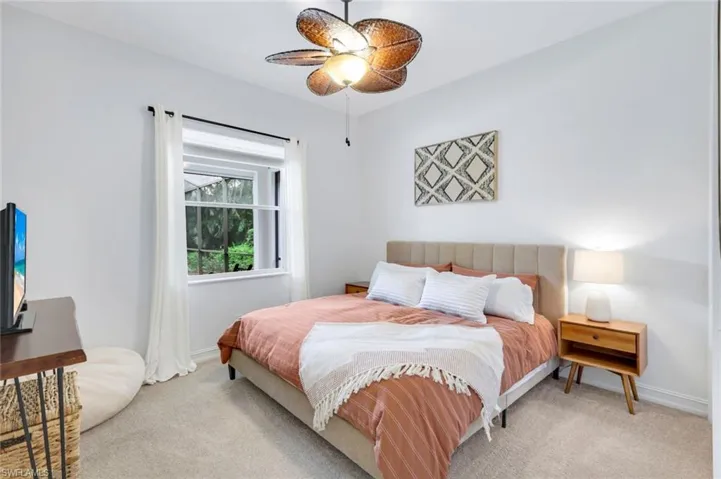 Carpeted bedroom with a ceiling fan and baseboards
