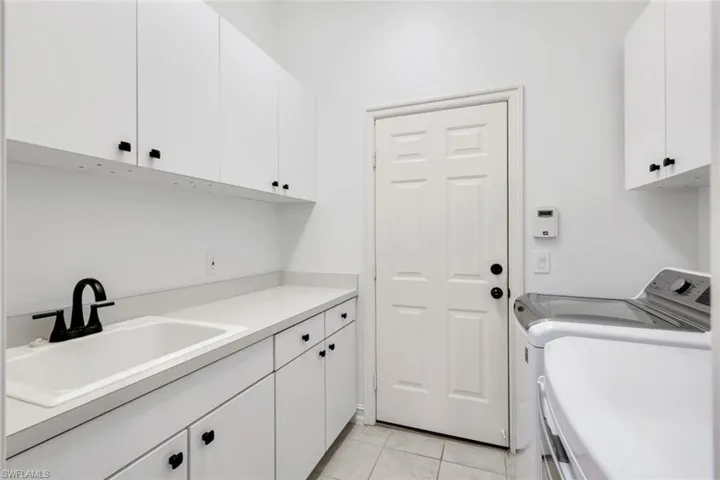 Washroom with cabinet space, light tile patterned flooring, and separate washer and dryer