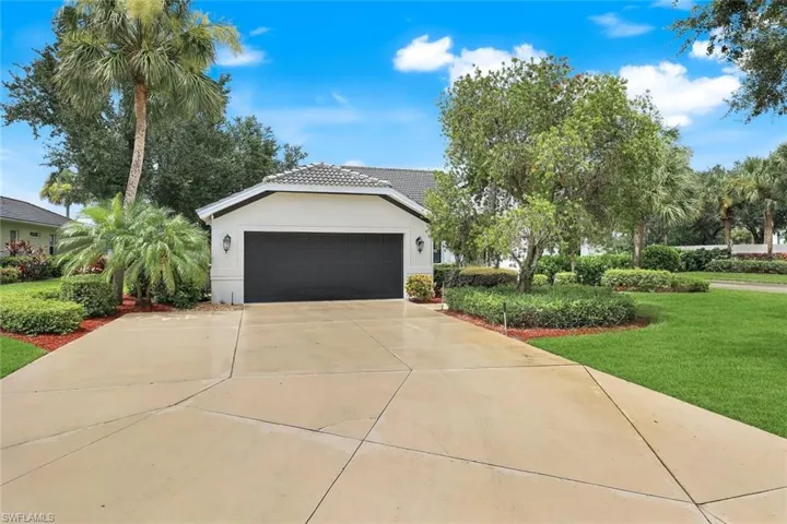 View of front of house featuring an attached garage, driveway, a front yard, stucco siding, and a tiled roof