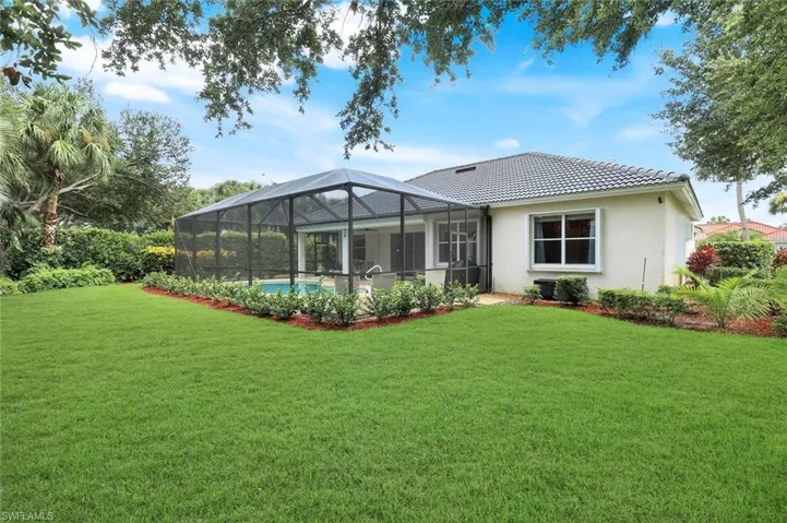 Back of house with a yard, and a tile roof