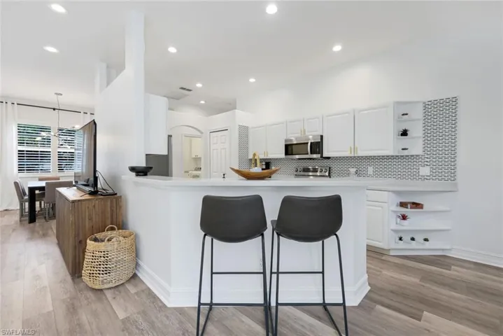 Kitchen featuring open shelves, a kitchen bar, white cabinetry, and recessed lighting