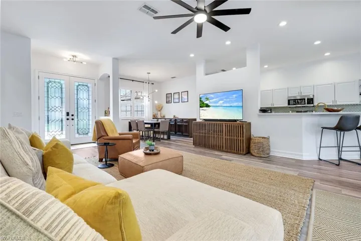 Living room with french doors, light wood-style LVT floors, recessed lighting, and ceiling fan