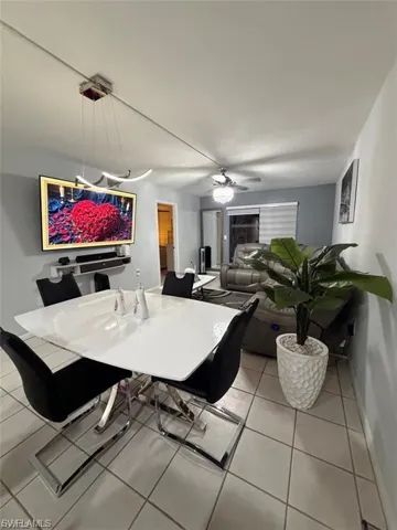 Open-concept dining area featuring a contemporary chandelier, white tile flooring, and a modern dining table