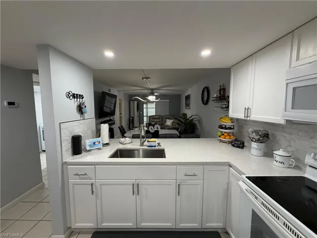 Modern kitchen featuring white shaker cabinetry, light-toned countertops, and a subway tile backsplash