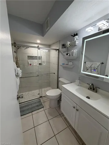 Bathroom featuring a walk-in shower with glass enclosure, white subway tile walls, and a mosaic accent