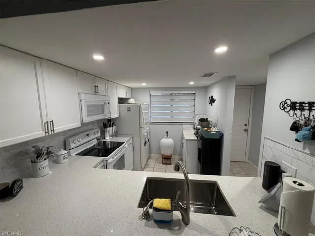 Modern kitchen featuring light-toned cabinetry, a stainless steel undermount sink, and light-colored countertops