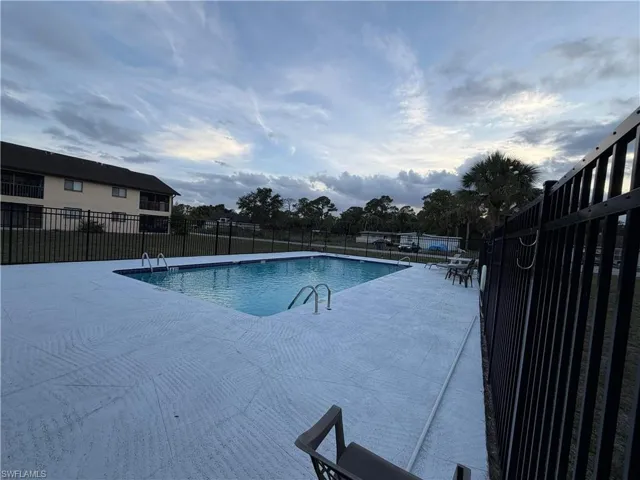 Rectangular swimming pool featuring a light-colored, textured deck surround and metal access ladders