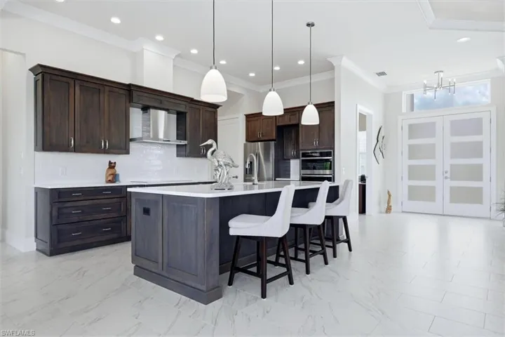 Gourmet kitchen with dark wood cabinetry, white subway tile backsplash, stainless steel appliances, and a central island with pendant lighting