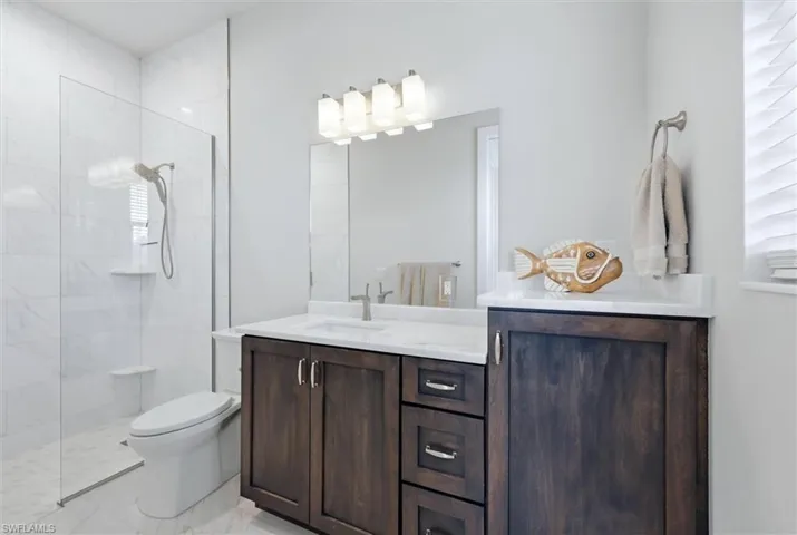 Walk-in shower with a glass enclosure and white tile surround