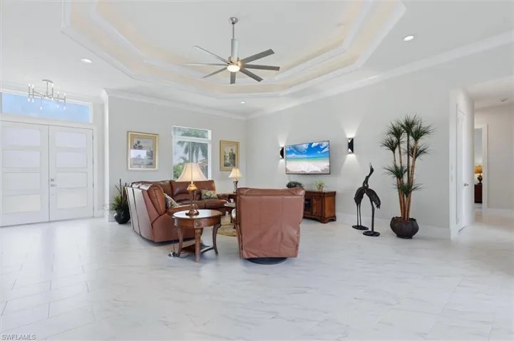 White tile flooring, double entry doors with transom window, recessed lighting, and a multi-tiered tray ceiling with a ceiling fan