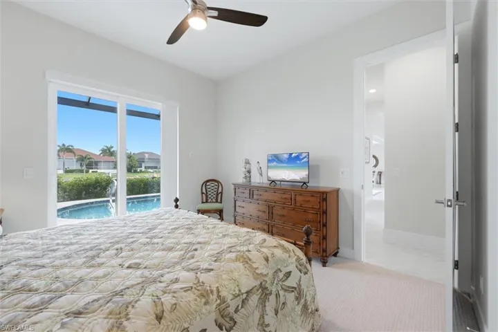 Sliding glass doors opening to a screened lanai with a swimming pool, complemented by a ceiling fan with integrated lighting