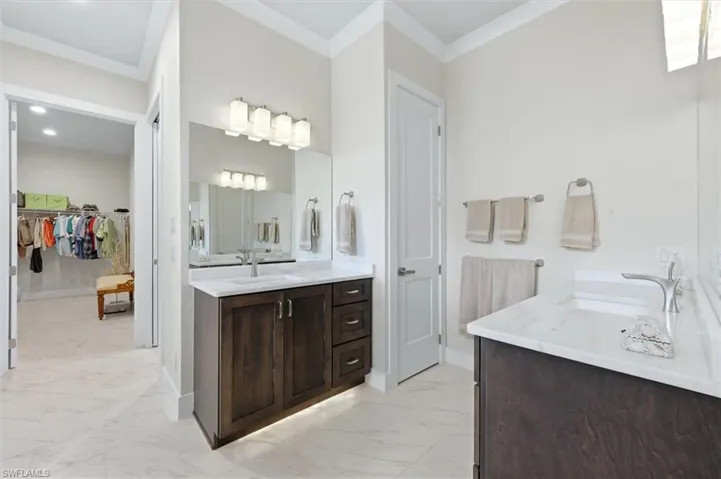 Dual vanity with integrated sinks, dark wood-finish cabinetry, white countertop, and matching wall-mounted light fixtures