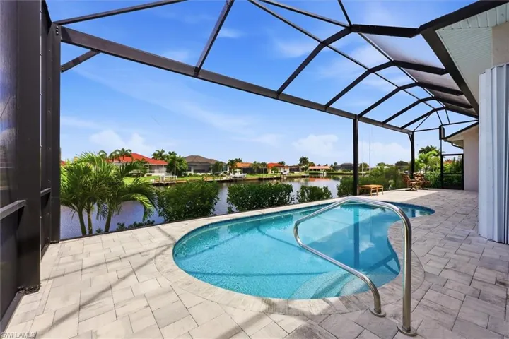 Screened patio with a freeform pool, integrated spa, and pavers