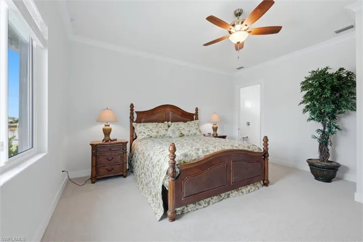 White walls with crown molding, light-colored carpet flooring, a single window, and a ceiling fan with integrated lighting