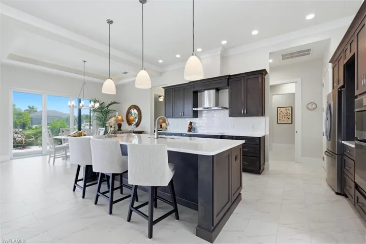 Tray ceiling, recessed lighting, expansive glass sliding doors, dark wood-finish cabinetry, and stainless steel appliances