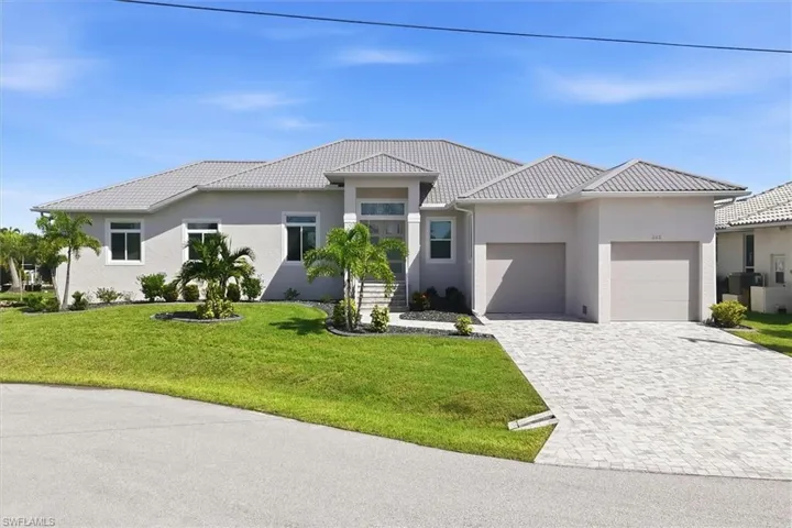 Stucco exterior with a tile roof, paver driveway, and a two-car garage