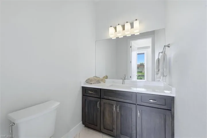 Vanity with dark wood-finish cabinetry, white countertop, and integrated rectangular sink
