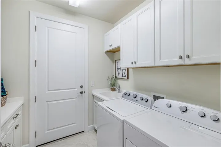 Large laundry with folding station, washing sink, tons of cabinerty and access to garage