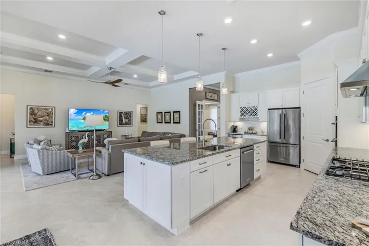 Kitchen featuring an oversized island with sink, appliances with stainless steel finishes, and white cabinetry