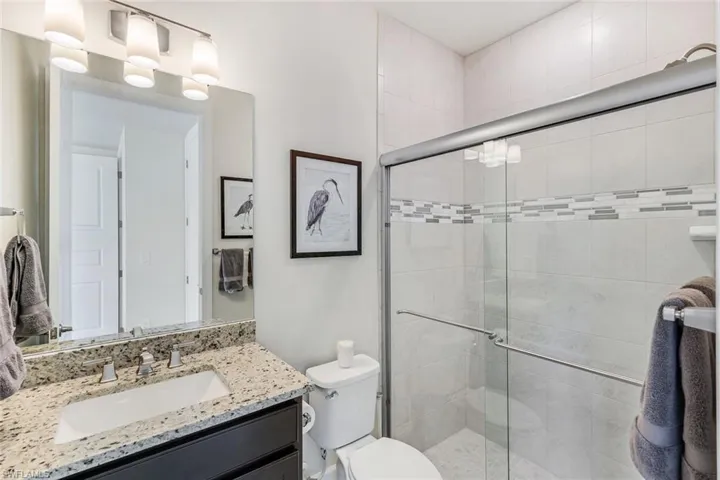 3rd bedroom ensuite bathroom featuring walk in shower, granite topped vanity, and toilet