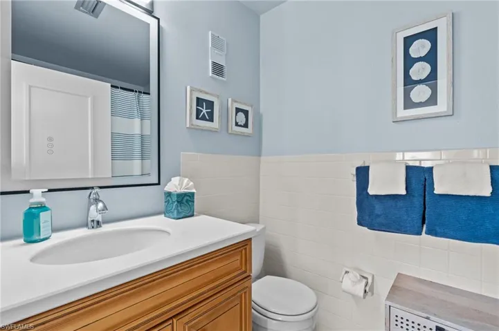 Bathroom featuring vanity, curtained shower, tile walls, and a wainscoted wall