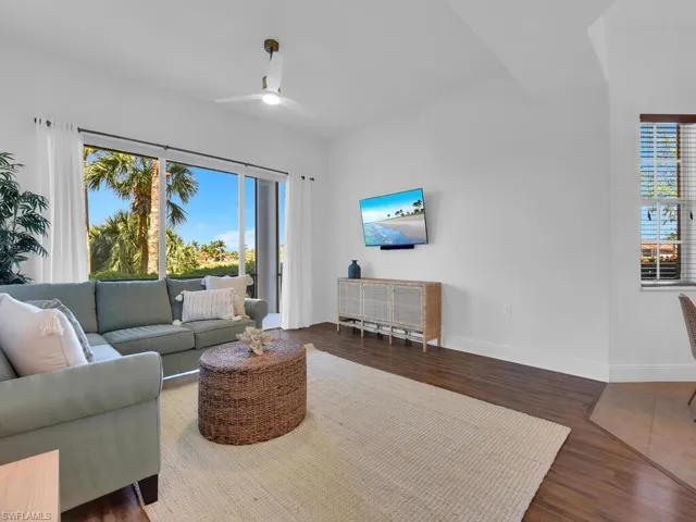 Living area with a healthy amount of sunlight, wood finished floors, baseboards, and a ceiling fan