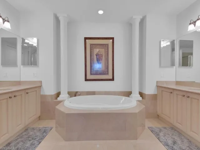 Bathroom featuring a sink, two vanities, a bath, and ornate columns