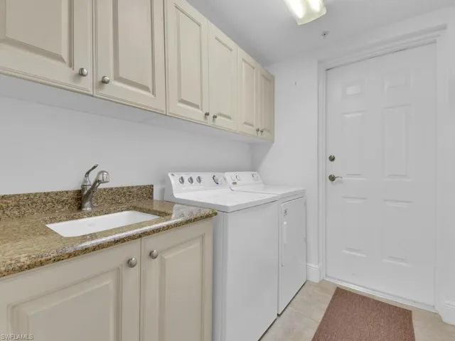 Washroom with light tile patterned floors, a sink, cabinet space, and washing machine and dryer