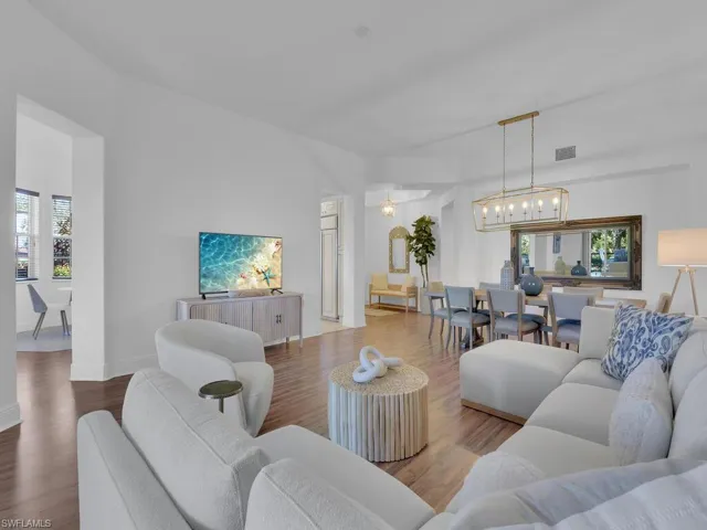 Living area featuring baseboards, visible vents, wood finished floors, and a chandelier