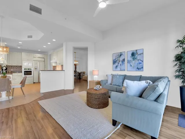 Living area featuring recessed lighting, ceiling fan with notable chandelier, baseboards, visible vents, and light wood-style flooring