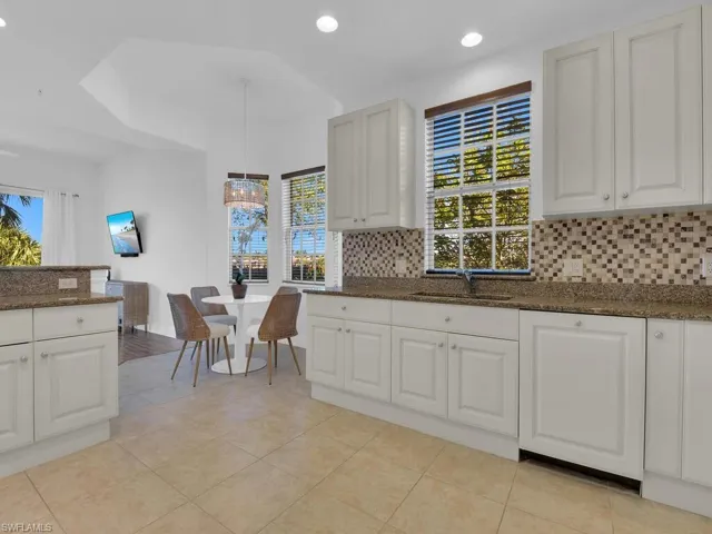 Kitchen with plenty of natural light, tasteful backsplash, dark stone countertops, and a sink