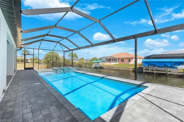 Integrated pool / spa featuring glass enclosure, a patio, a sunroom, a water view, and a boat dock
