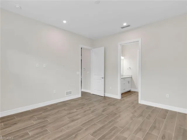Unfurnished bedroom featuring ensuite bathroom, wood finish floors, and recessed lighting