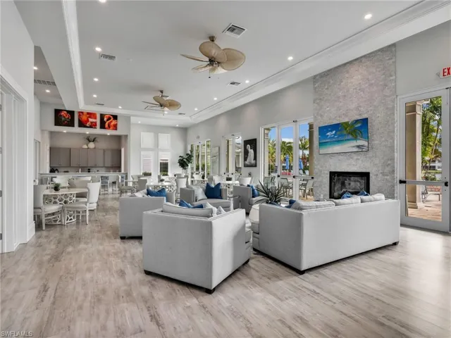 Living area featuring light wood-type flooring, a stone fireplace, plenty of natural light, a ceiling fan, and recessed lighting