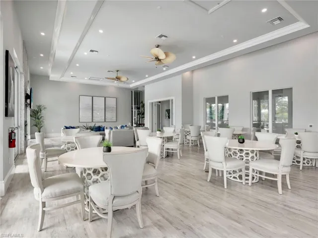Dining room with a raised ceiling, a ceiling fan, recessed lighting, and light wood-style flooring