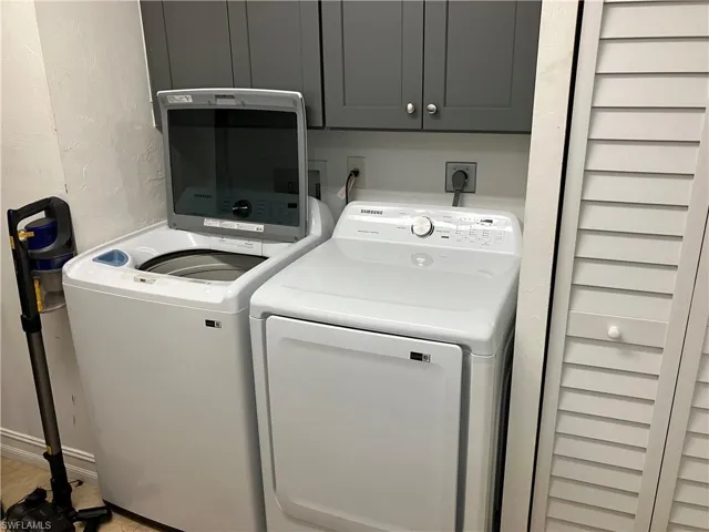 Laundry area featuring a textured wall, washer and dryer, and cabinet space
