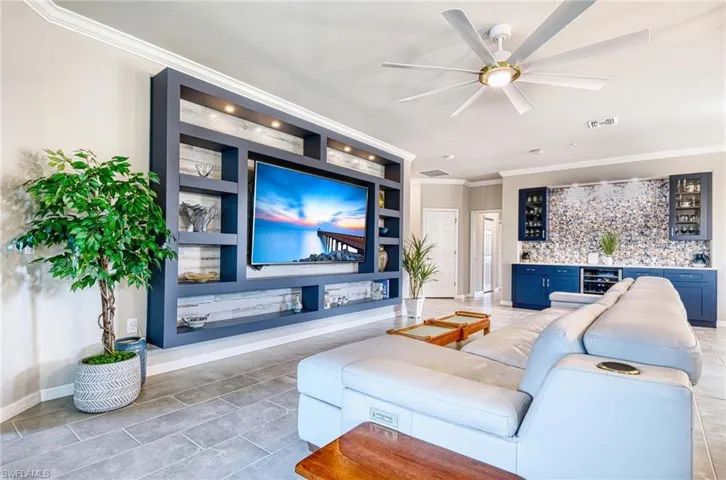 Living area featuring built in features, crown molding, bar area, a ceiling fan, and wine cooler