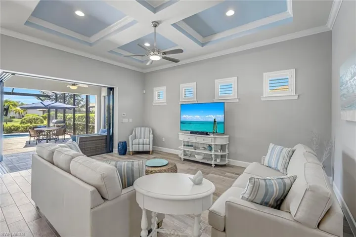 Living room featuring a sunroom, healthy amount of natural light, crown molding, coffered ceiling, and a ceiling fan