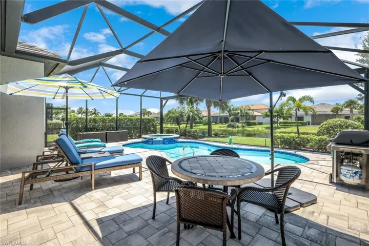 View of swimming pool with a pool with connected hot tub, a patio area, grilling area, and glass enclosure