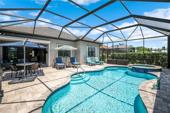 View of pool featuring a patio area, a pool with connected hot tub, and glass enclosure