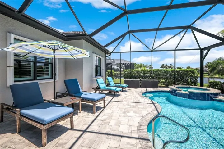 View of pool featuring a patio area, a pool with connected hot tub, and glass enclosure