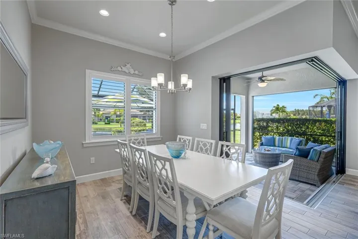 Dining space with ornamental molding, light wood finished floors, a ceiling fan, recessed lighting, and a chandelier