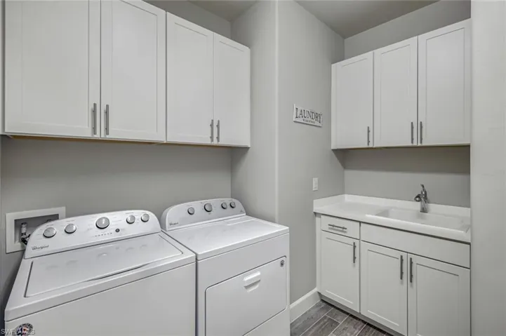 Laundry area featuring cabinet space, independent washer and dryer, and wood finished floors