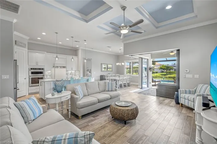 Living area with recessed lighting, coffered ceiling, ornamental molding, a ceiling fan, and light wood-style floors