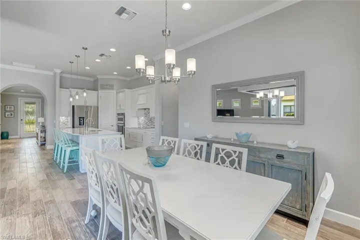 Dining room featuring ornamental molding, a chandelier, light wood-style flooring, arched walkways, and recessed lighting