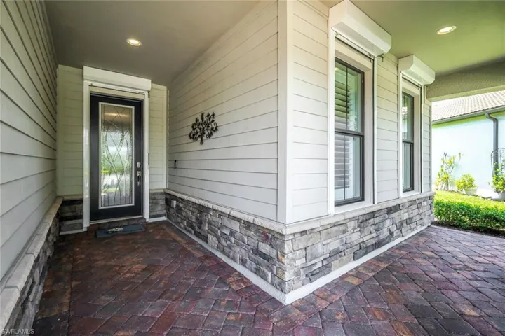 View of exterior entry with stone siding and covered porch