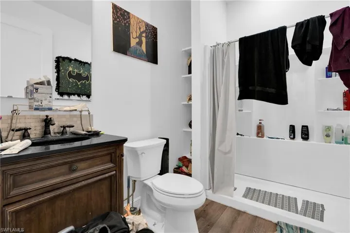 Bathroom with a stall shower, vanity, wood finished floors, and tasteful backsplash